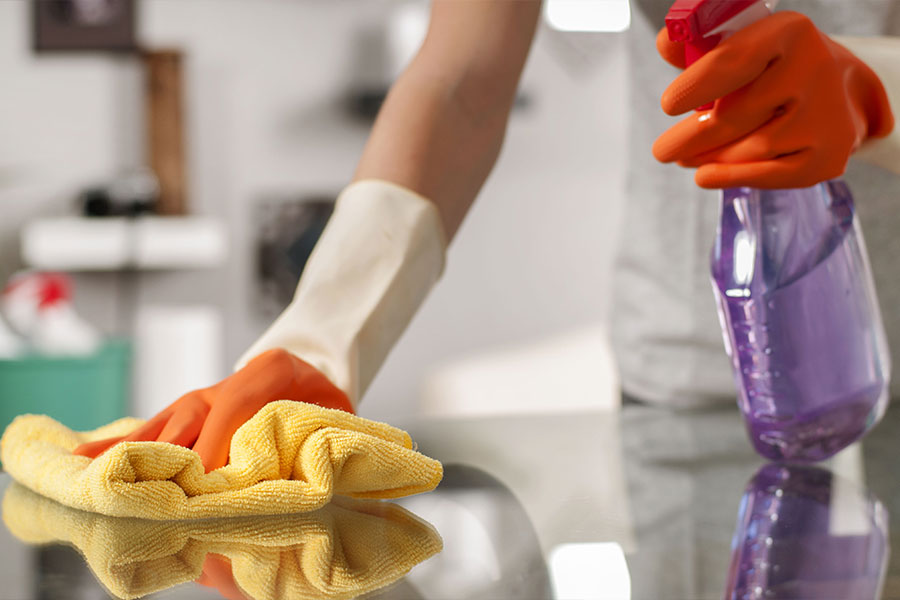 A professional cleaning maid in a residential home in St. Charles, MO wiping down a kitchen counter with eco-friendly cleaning products.