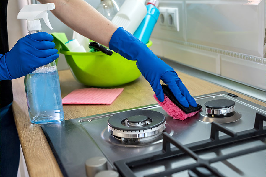 A professional cleaner wiping down a stove with quality cleaning products in St. Charles, MO.