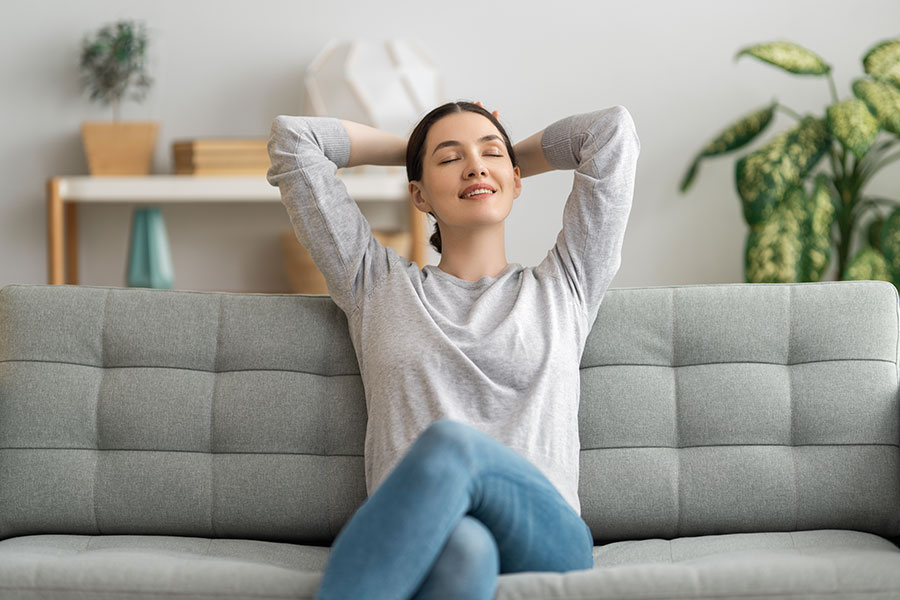 A happy homeowner sitting in their home with crossed arms and eyes closed enjoying a clean home in St. Charles, MO after a maid cleaning service.