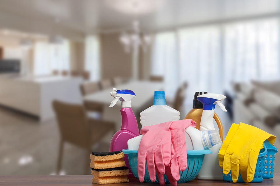 Various cleaning tools sitting on a table in front of an ample, clean living space in O’Fallon, MO.