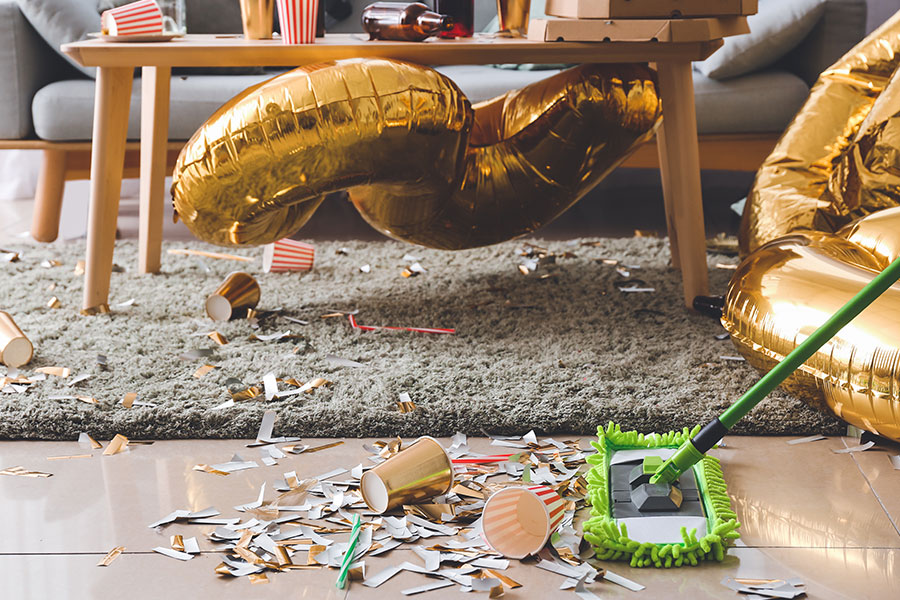 A residential homeowner in St. Peters, MO using a green broom to sweep up New Year party decorations.