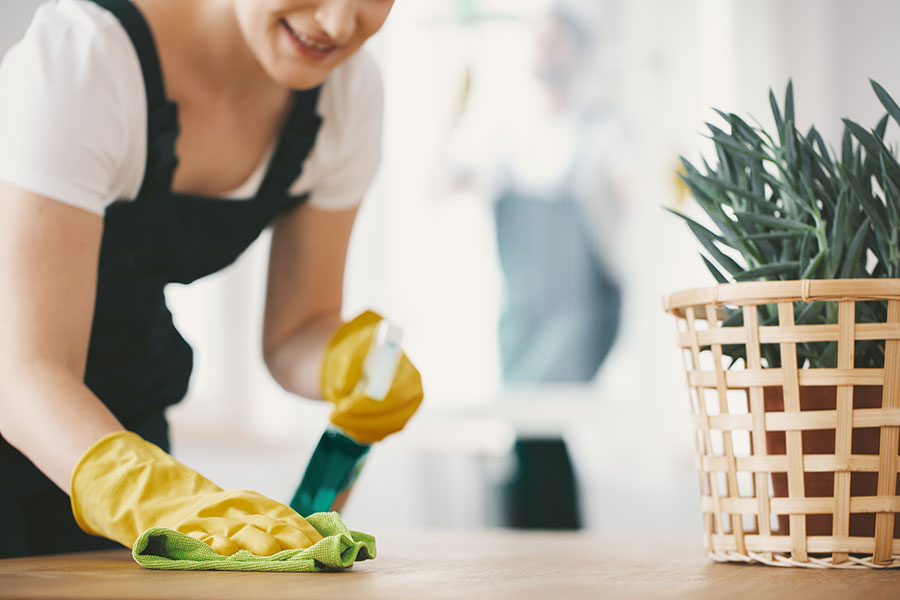 An experienced and trained maid that is wiping down a table with a green rag and yellow gloves for a vacation rental property in St. Charles, MO.