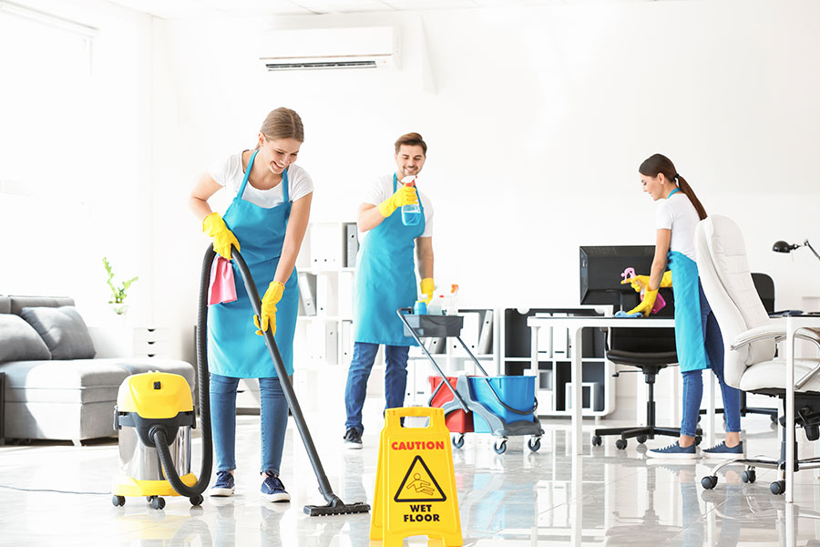 A team of professional cleaners in blue aprons using commercial equipment and products to clean a commercial space in St. Charles, MO.
